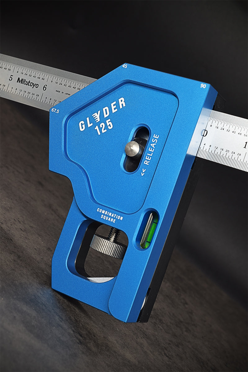A red and silver combination square tool with a metallic ruler, designed for precision measuring and marking in woodworking or engineering.