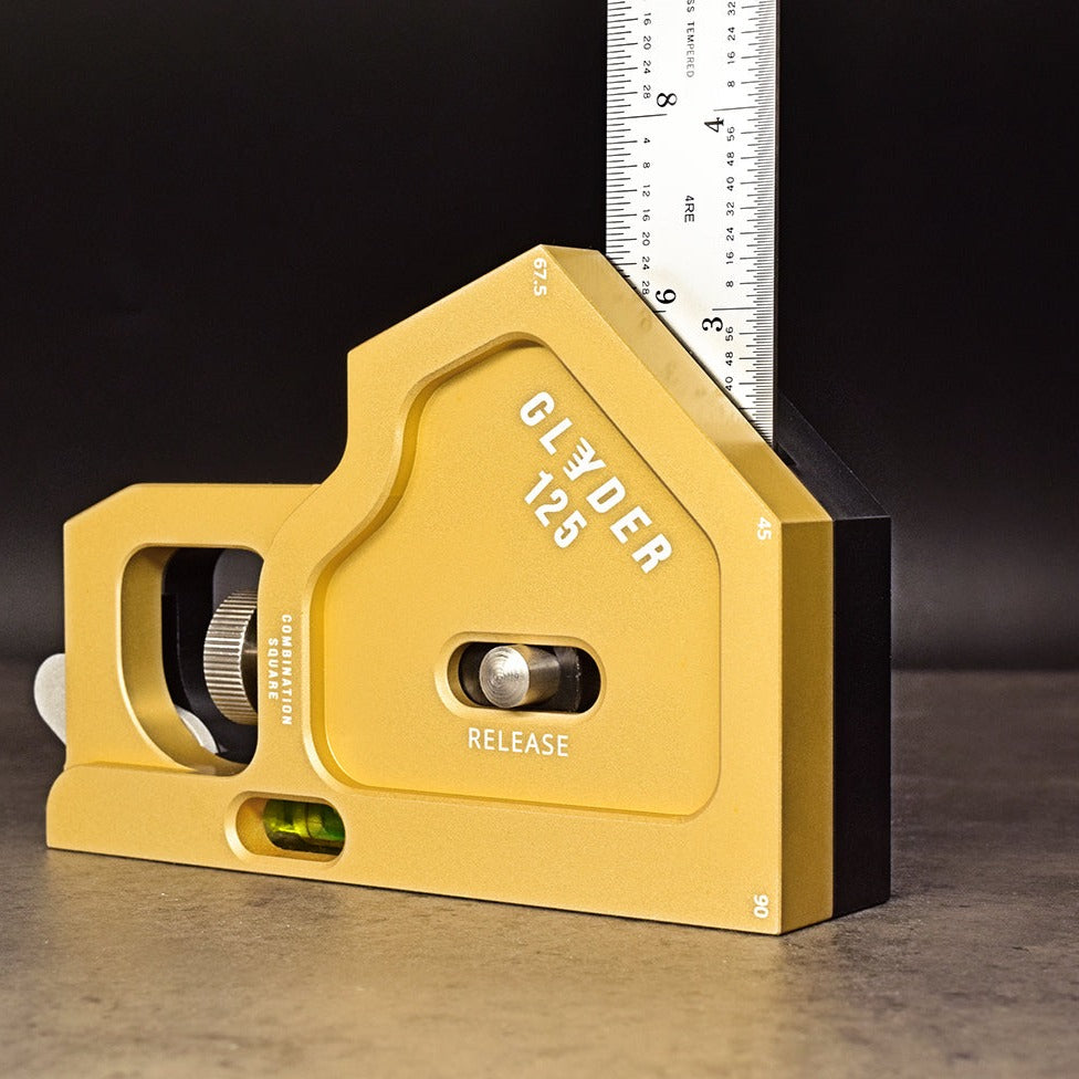 A yellow and silver combination square tool with a metallic ruler, designed for precision measuring and marking in woodworking or engineering.